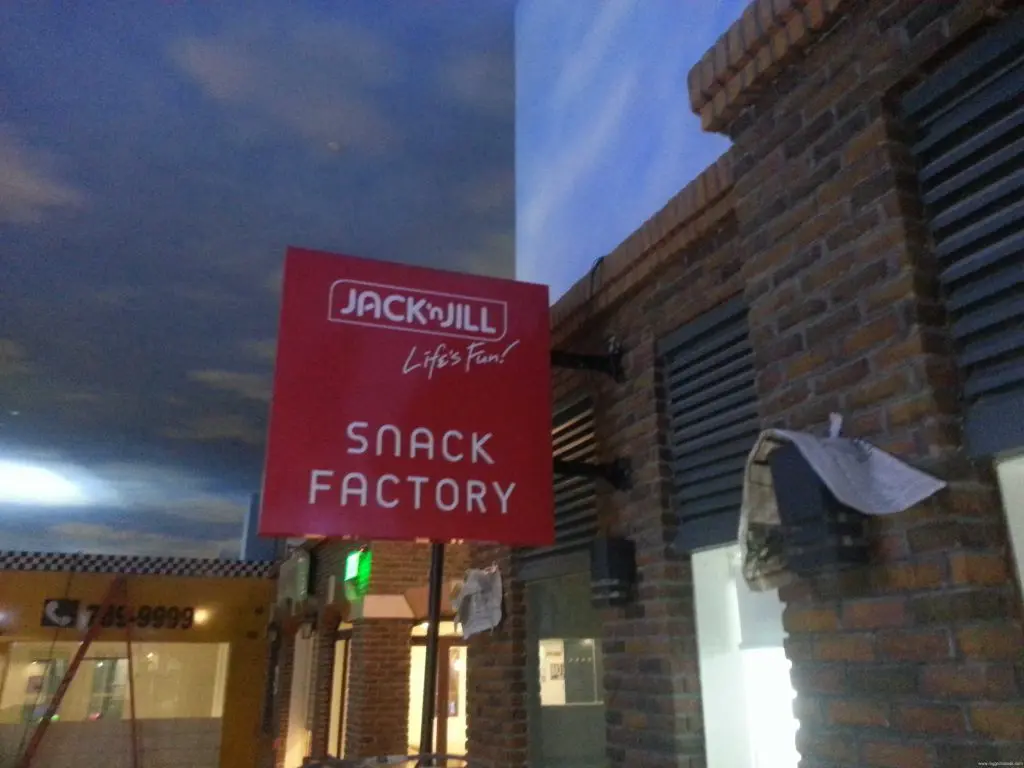 Jack n Jill Snack Factory red outdoor signage on brick building in Makati, blue sky background by M&G Global Ads.