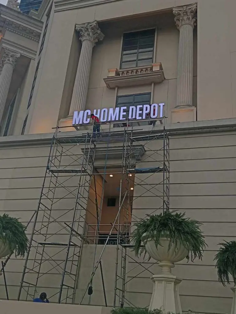 Outdoor MC HOME DEPOT signage installation by workers on scaffolding in Mandaluyong, classical building facade by M&G Global Ads.