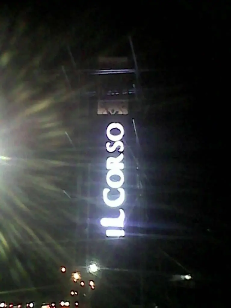 Vertical white neon signage for IL CORSO on a tall tower at night in BGC, with light flares, by M&G Global Ads.