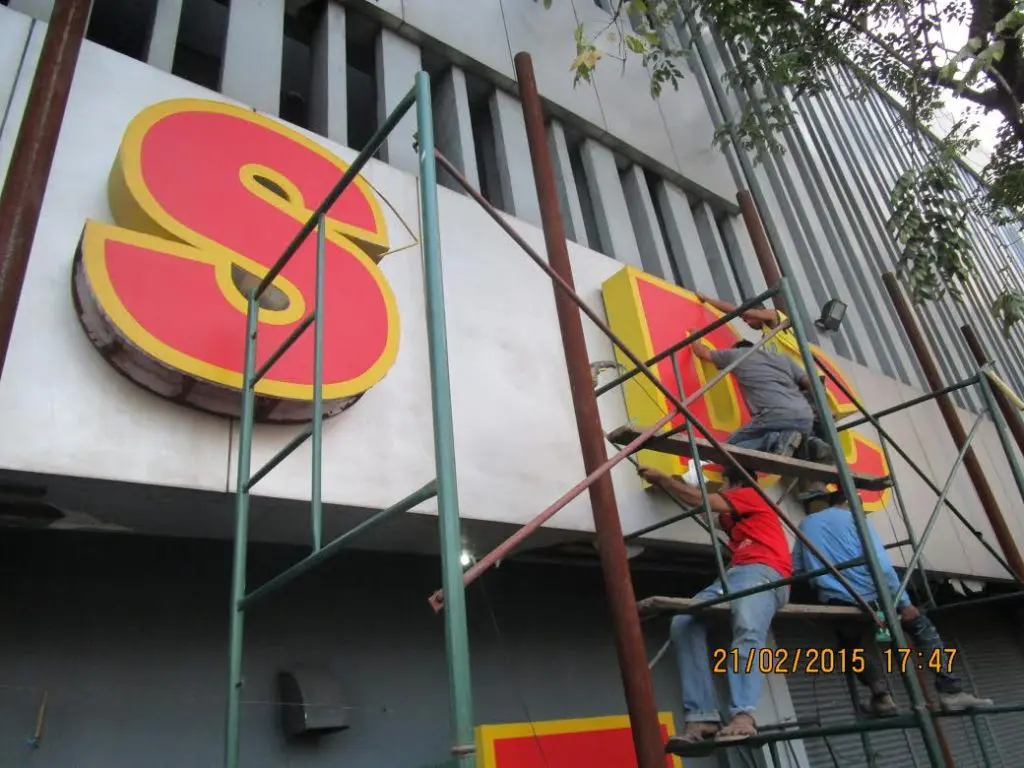 Channel letter signage installation by workers on scaffolding, Makati exterior building wall. Photo by M&G Global Ads.
