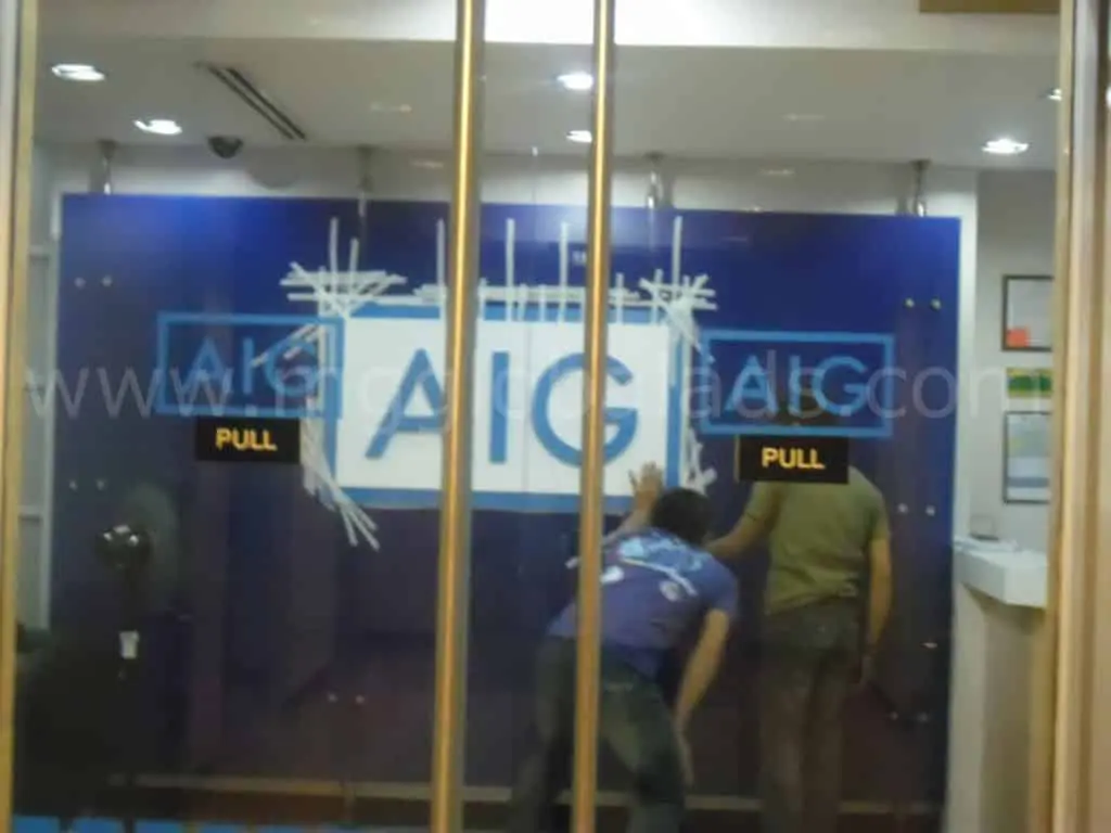 AIG indoor lobby signage on a blue wall in Metro Manila office, partially covered by tape, by M&G Global Ads.