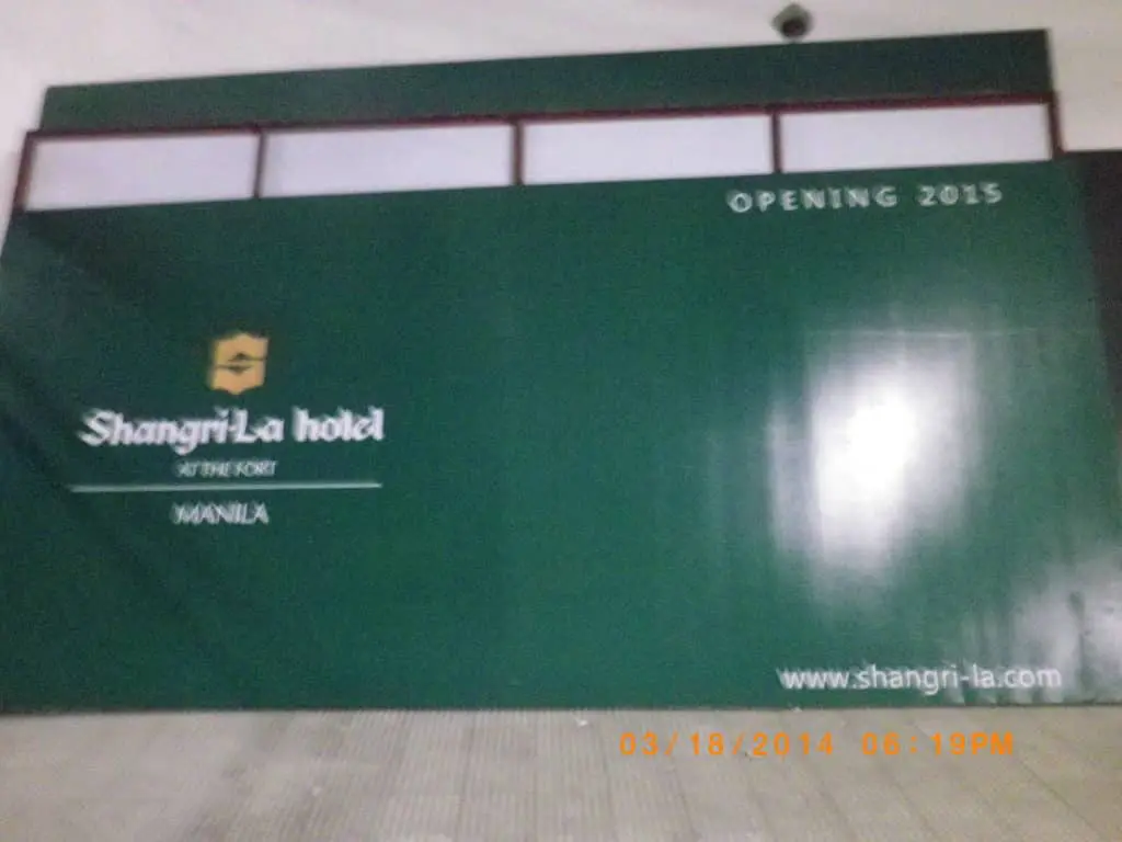 Shangri-La at the Fort Manila building signage on a green construction wall, promoting the 2015 opening by M&G Global Ads.