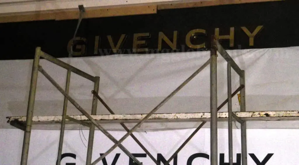 Outdoor acrylic signage for GIVENCHY in Makati with gold and black letters, metal scaffolding in front, by M&G Global Ads.
