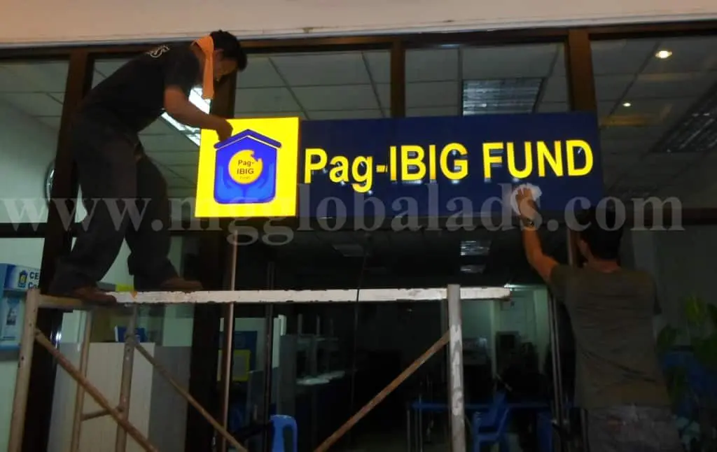 Pag-IBIG FUND illuminated outdoor signage installation in Quezon City at night, glass office building exterior by M&G Global Ads.