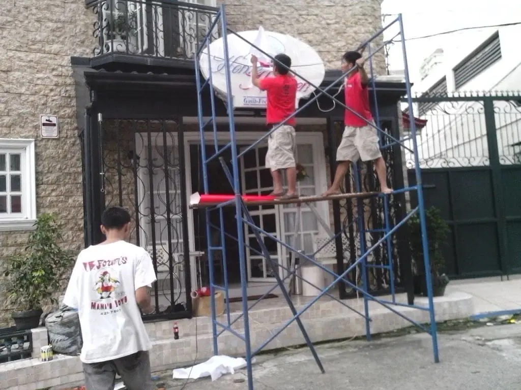 LED signage installation at a building entrance in Makati using blue scaffolding, stone facade, black gate by M&G Global Ads.