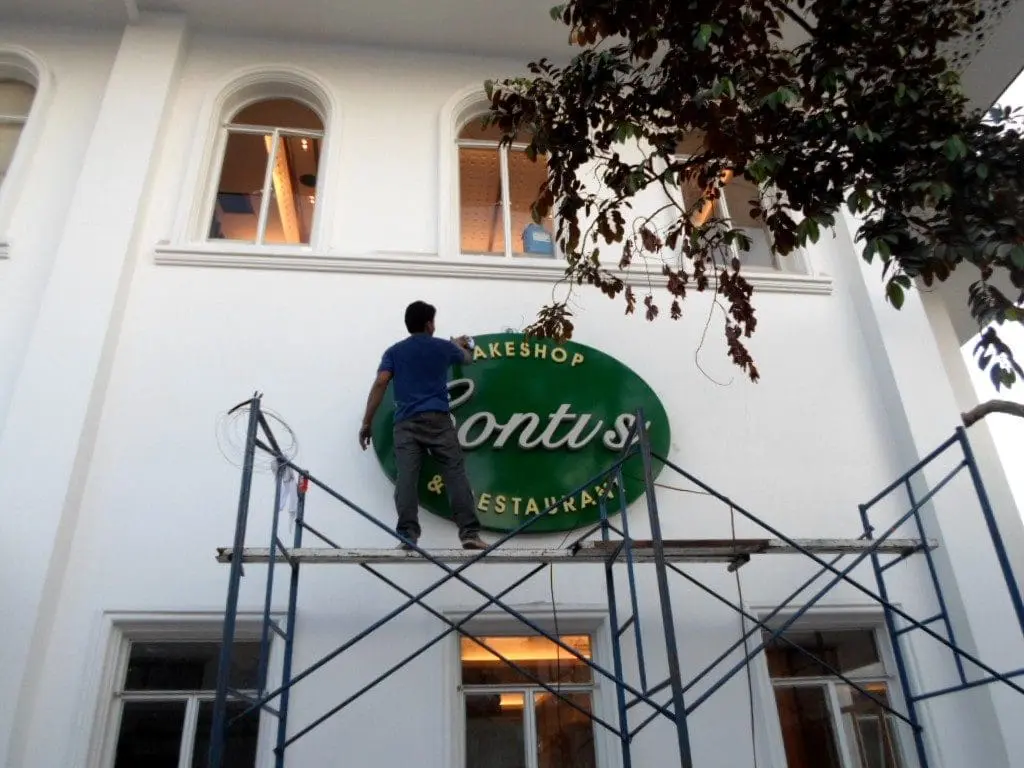 Acrylic bakery and restaurant signage installation on a white exterior wall in Quezon City by M&G Global Ads.