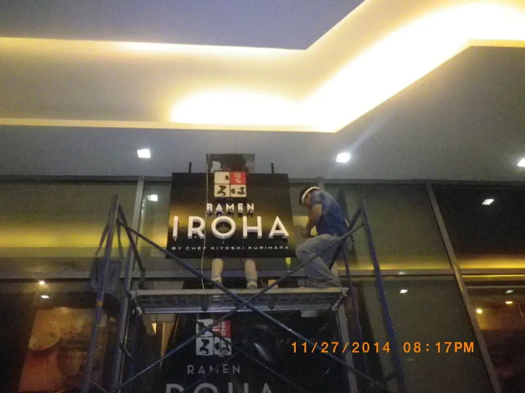 Illuminated acrylic signage for Ramen Iroha installed indoors by worker in Makati at night by M&G Global Ads.