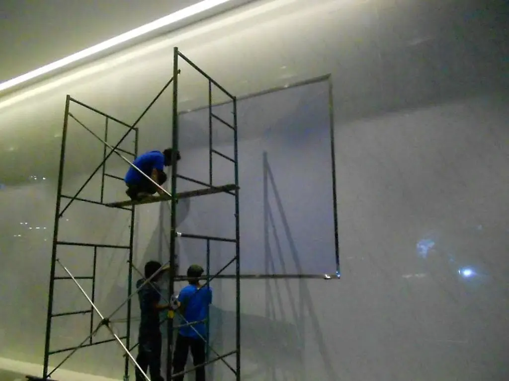 Acrylic signage installation for a client in Makati, with workers on scaffolding indoors and well-lit by M&G Global Ads.
