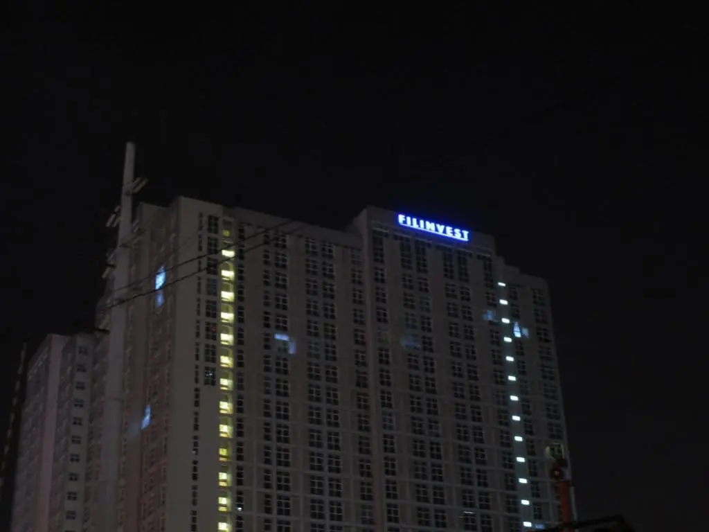 LED building signage for FILINVEST lights up a tall, windowed structure at night in Makati by M&G Global Ads.