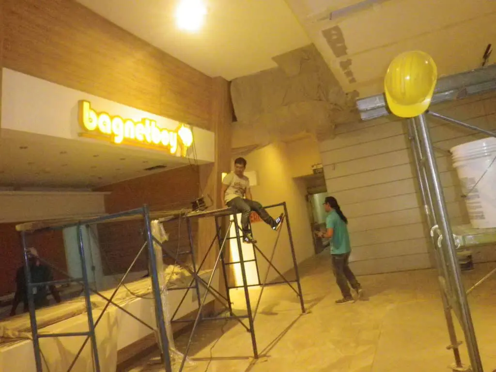 Workers install LED signage inside a building under construction in Makati, with tools and gear on site, by M&G Global Ads.