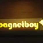 Glowing yellow outdoor building signage for Bagnetboy with pig on fork, wood background, Makati location by M&G Global Ads.