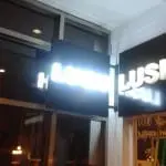 Acrylic outdoor signage for LUSH glows at night in Makati, with a person by the store entrance. By M&G Global Ads.