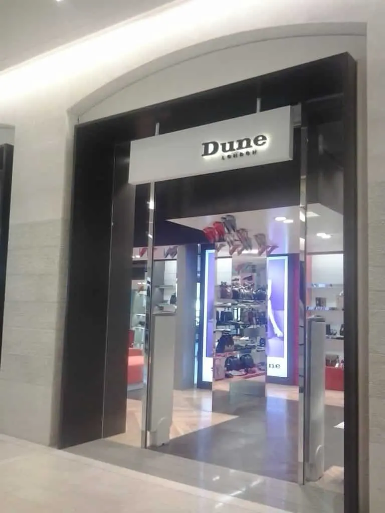 Dune London storefront with illuminated outdoor signage and glass doors in Makati mall, shoes and bags on display by M&G Global Ads.