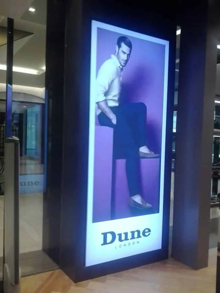 Backlit indoor signage for Dune London, store display in Makati with man on purple block, vibrant look by M&G Global Ads.