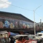 Outdoor Kikkoman banner signage at busy market scene in Quezon City, showing food images and slogan, by M&G Global Ads.
