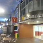 McDonalds lighted building signage in Quezon City indoor branch, with empty tables, lamp post, and bins. By M&G Global Ads.