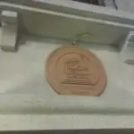 Round metallic Supreme Court office sign with cartoon judge on stone wall in Quezon City, by M&G Global Ads. Slightly blurred.