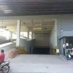 Delivery area with outdoor directional signage and height clearance signs in Makati, motorcycle, people outside. By M&G Global Ads.