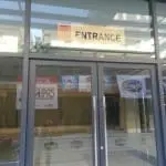 Entrance building signage glass double doors in Makati with reflections of banners, by M&G Global Ads.