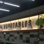 Illuminated LED VEGETABLES signage in a grocery store, tiled wall, lights, worker on scaffolding in Quezon City by M&G Global Ads.