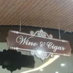 Metallic hanging sign for Wine & Cigar in elegant script, seen in Makati, by M&G Global Ads.
