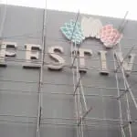 Acrylic FESTIVA building signage with colorful petals, installation in progress in Pasig, by M&G Global Ads.