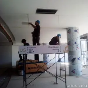 Directional indoor mall signage installation for H&M in Makati with construction workers on scaffolding by M&G Global Ads.