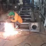 Acrylic signage fabrication workshop in Mandaluyong, worker welding with bright sparks, others assembling by M&G Global Ads.