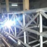 LED signage welding in industrial workshop, pipes and machinery visible, Ortigas location by M&G Global Ads.