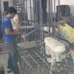 Construction workers assembling steel rebar indoors with safety signage for M&G Global Ads client in Makati, by M&G Global Ads.