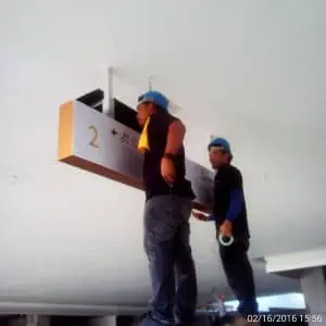 LED overhead signage installation by two workers in blue helmets, Ortigas site, indoor construction, by M&G Global Ads.