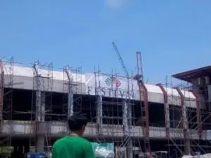 Acrylic FESTIVAL signage with colorful logo on construction site in BGC, man in green shirt nearby, by M&G Global Ads.
