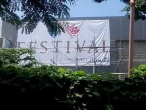 Outdoor event signage banner reading FESTIVAL with colorful leaves in Makati, partially covered by foliage—by M&G Global Ads.