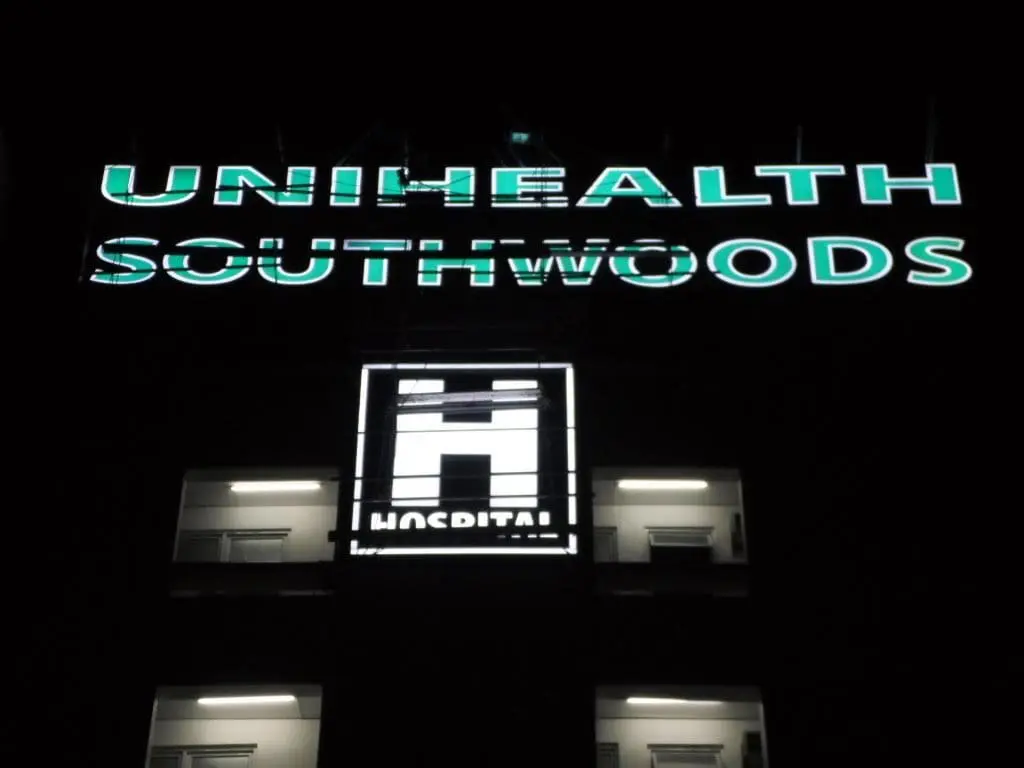 Acrylic signage for UNIHEALTH SOUTHWOODS being cleaned by workers on tall building, Makati location, by M&G Global Ads.