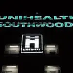 Acrylic signage for UNIHEALTH SOUTHWOODS being cleaned by workers on tall building, Makati location, by M&G Global Ads.