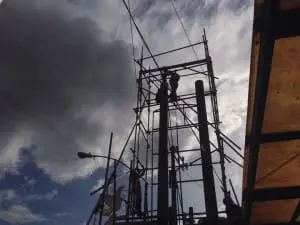 Building pylon signage under construction in Makati with scaffolding, green netting, No Parking sign by M&G Global Ads.