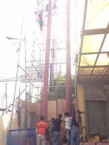 Designer in black shirt and glasses brainstorming indoor signage ideas for Ortigas offices, beige background, by M&G Global Ads.