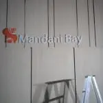 Mandani Bay outdoor building signage with red circular logo in Makati; metal signage, ladder & shadow by M&G Global Ads.