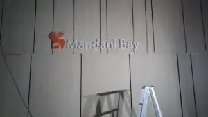 Mandani Bay outdoor building signage with red circular logo in Makati; metal signage, ladder & shadow by M&G Global Ads.