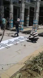 Large white acrylic building signage being assembled by two workers in Quezon City. Construction site. By M&G Global Ads.