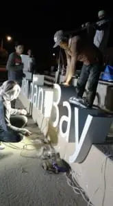 LED signage installation for Bay at night in Makati, workers wiring illuminated letters on metallic sign by M&G Global Ads.