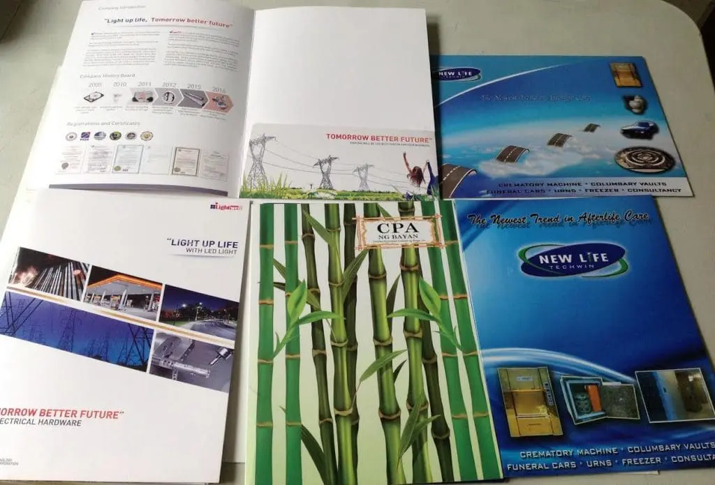 Metallic sign brochure designs and power line graphics for business in Makati, displayed on a table by M&G Global Ads.