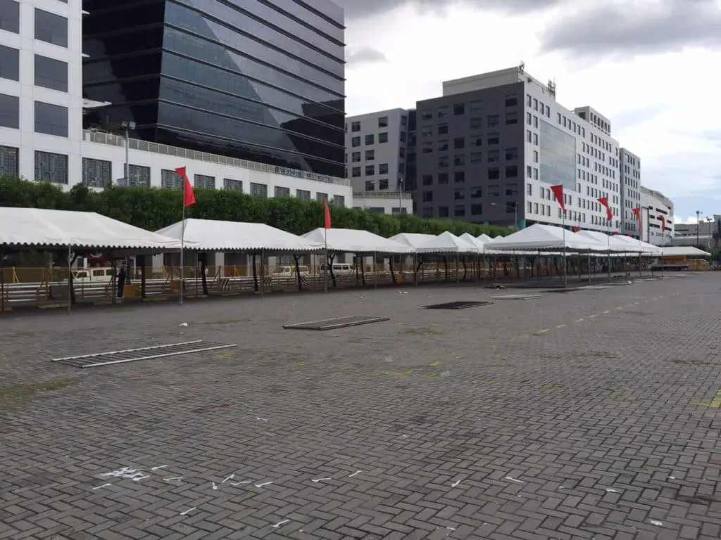 Outdoor stage with LED billboard signage, white canopy, and gray van at night in Quezon City, by M&G Global Ads.