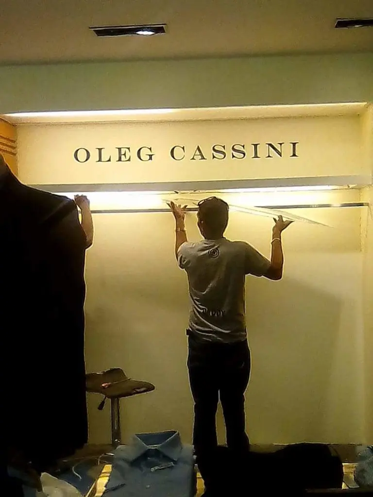 Metallic OLEG CASSINI store signage installation in Makati with glass shelf adjustment by M&G Global Ads.