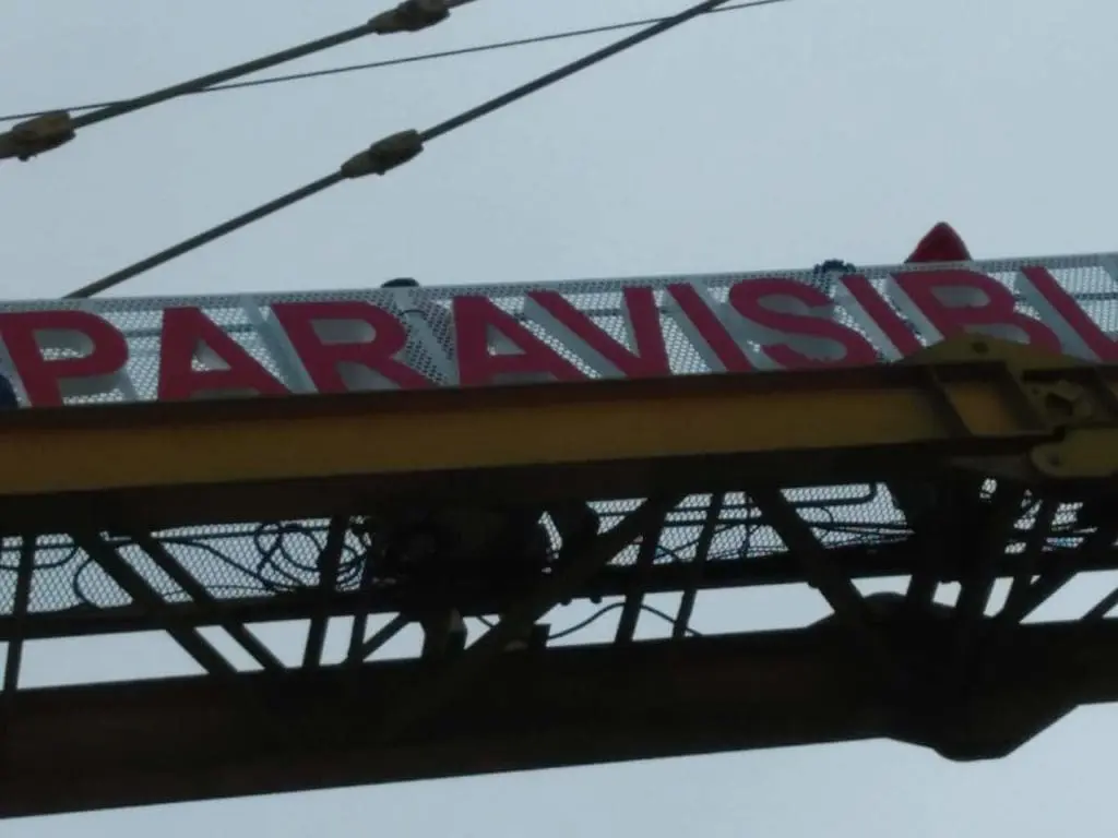 Outdoor billboard signage with red PARAVISI letters on white, metal frame, cloudy sky, in Makati by M&G Global Ads.