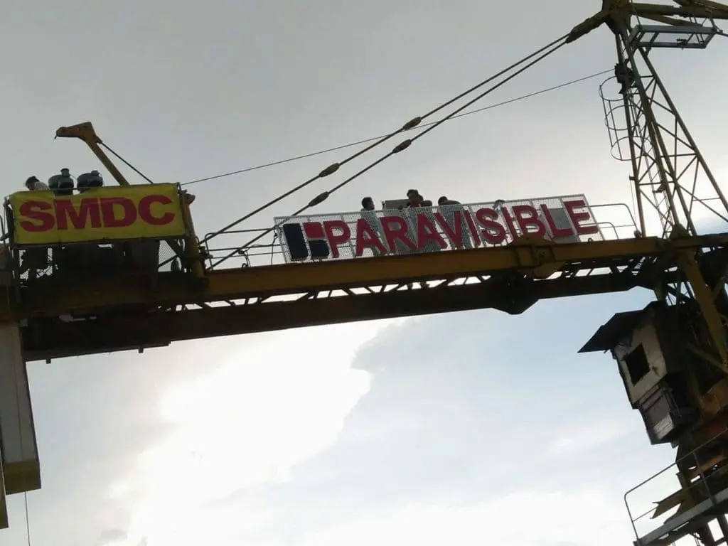 Outdoor crane signage for SMDC and PARAVISIBLE in Makati with banners, cloudy sky view by M&G Global Ads.