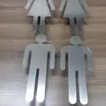 Metallic restroom signage for buildings, women and men figures on wood, Makati location by M&G Global Ads.