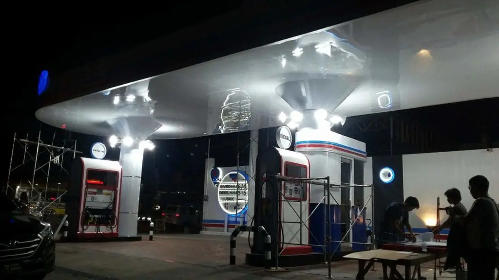Outdoor and acrylic gas station signage in Quezon City, with staff working under canopy at night, by M&G Global Ads.