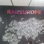 Rail Europe metallic logo signage on wall with dotted Europe map, in BGC, by M&G Global Ads. Part of a persons head visible.