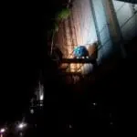 Worker installs illuminated building signage at night on scaffolding in Makati, minimal details visible. By M&G Global Ads.